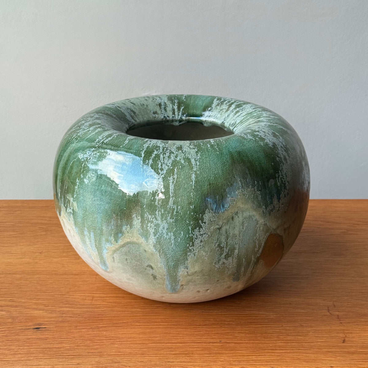Green and white ceramic bowl on a wooden surface with a plain background
