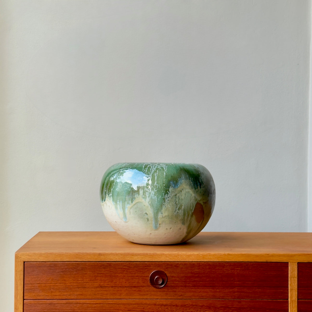 Green ceramic bowl on a wooden surface with a plain background