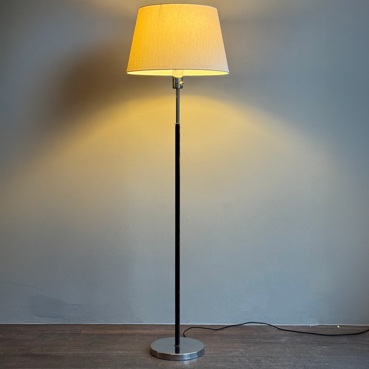 A vintage 1960s full-length floor lamp by Philips Netherlands, featuring a sleek steel frame complemented by leather accents. This mid-century modern design combines industrial materials with refined craftsmanship, offering both style and functionality.