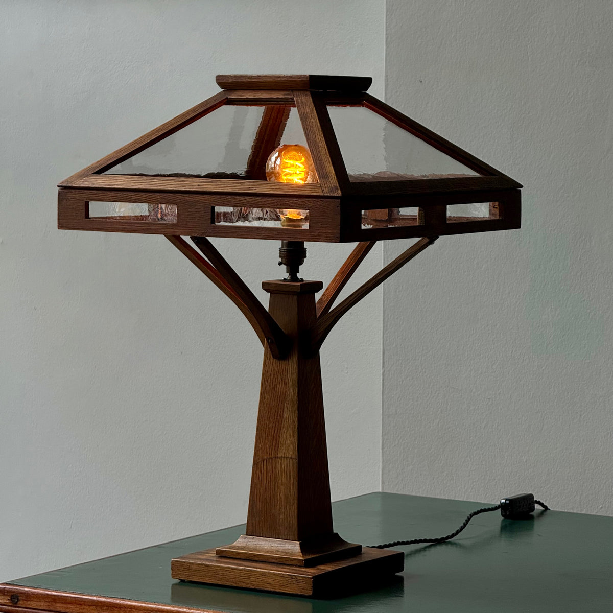 Wooden table lamp with a glass shade on a gray surface.