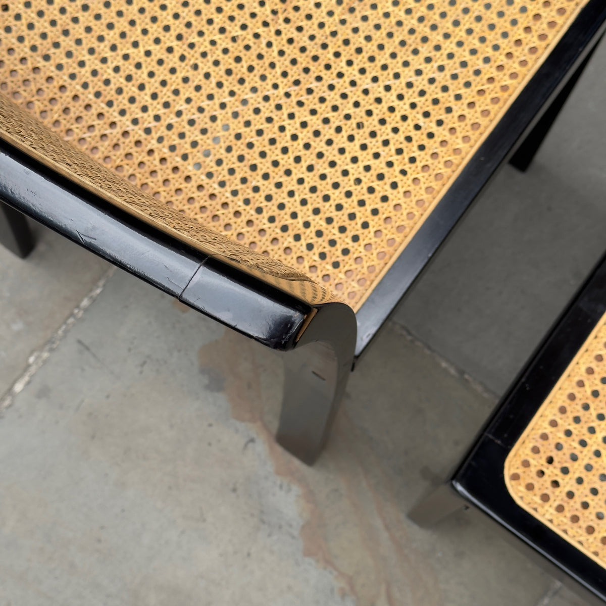 Detail of a Bankstuhl chair designed by Willy Guhl, featuring a sleek combination of black lacquered frames and cane seating. These chairs exemplify Guhl's innovative approach to design, blending elegant, modern aesthetics with functional comfort.