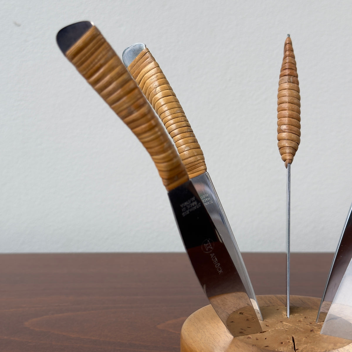 A Carl Auböck fruit knife set, with 6 cane wrapped fruit knives and a walnut wood base with cork insert. This piece is truly testament to the craftsmanship of the workshop.
