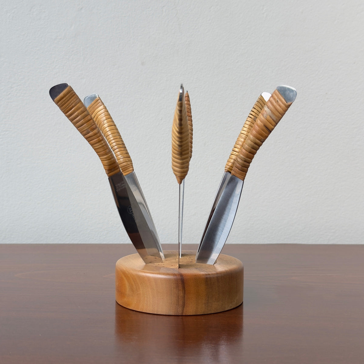 A Carl Auböck fruit knife set, with 6 cane wrapped fruit knives and a walnut wood base with cork insert. This piece is truly testament to the craftsmanship of the workshop. 