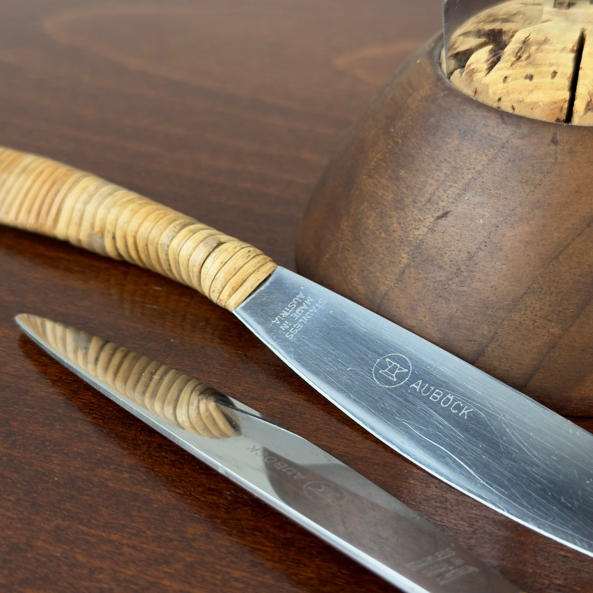 A vintage fruit knife set designed by Carl Auböck from the 1950s, featuring handles wrapped in cane. This full set exemplifies Austrian modernist design, combining functional elegance with the innovative use of natural materials, characteristic of midcentury modernism