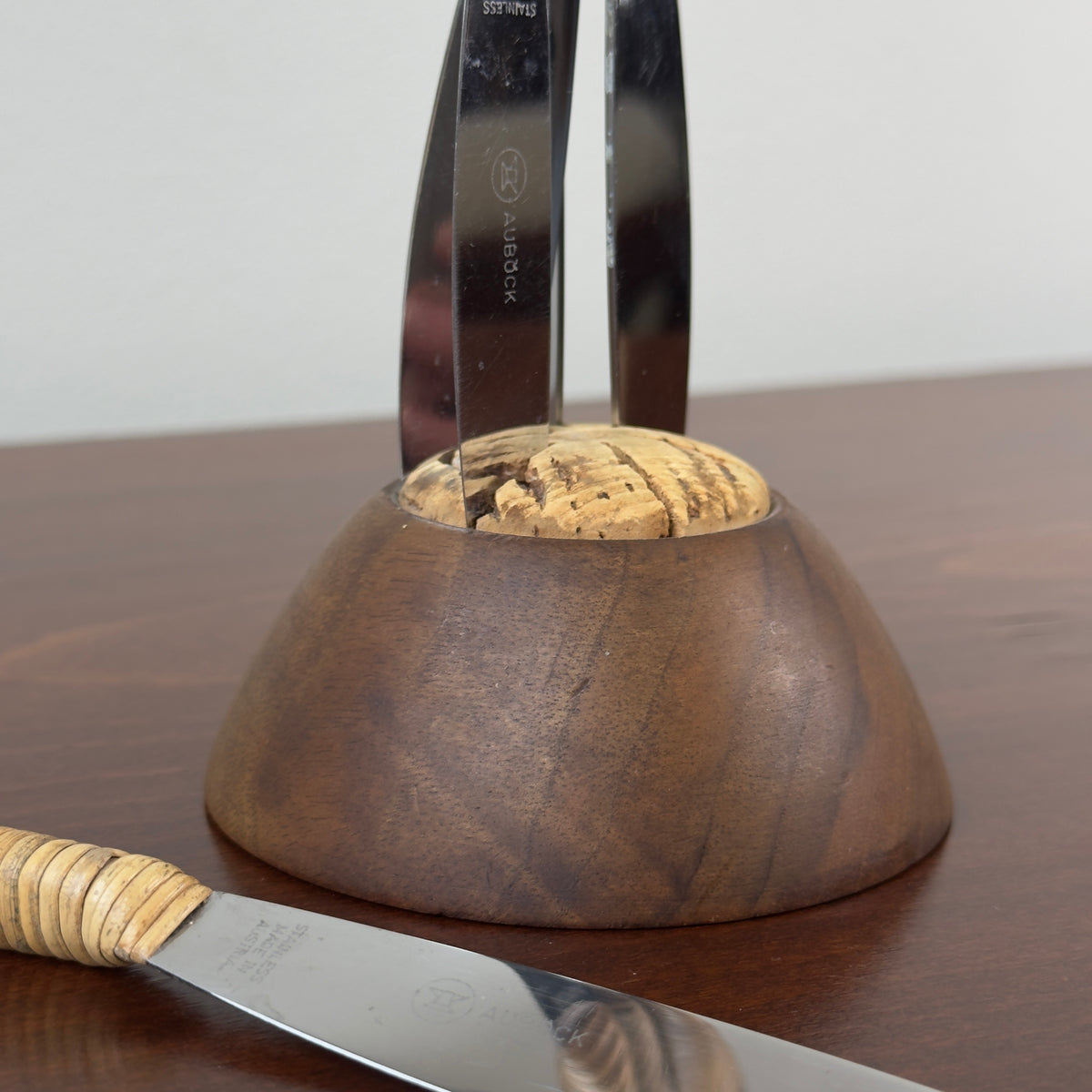 A vintage fruit knife set designed by Carl Auböck from the 1950s, featuring handles wrapped in cane. This full set exemplifies Austrian modernist design, combining functional elegance with the innovative use of natural materials, characteristic of midcentury modernism