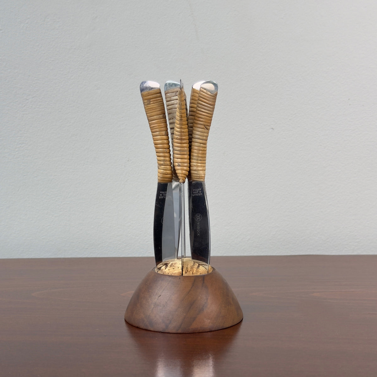 A vintage fruit knife set designed by Carl Auböck from the 1950s, featuring handles wrapped in cane. This full set exemplifies Austrian modernist design, combining functional elegance with the innovative use of natural materials, characteristic of midcentury modernism