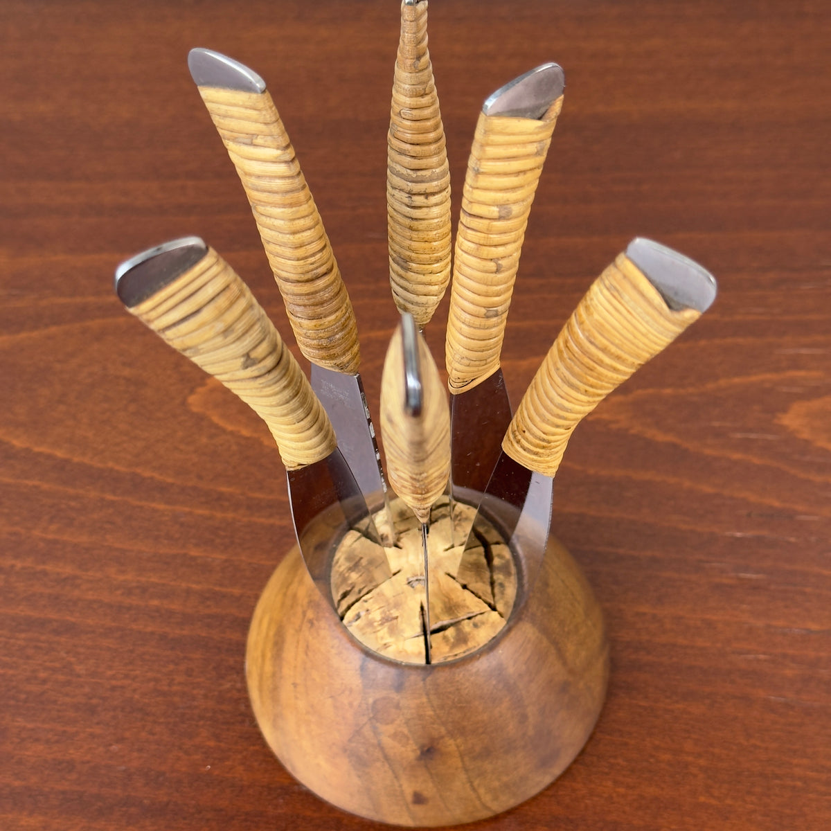 A vintage fruit knife set designed by Carl Auböck from the 1950s, featuring handles wrapped in cane. This full set exemplifies Austrian modernist design, combining functional elegance with the innovative use of natural materials, characteristic of midcentury modernism