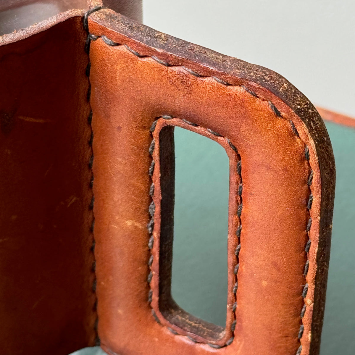A mouth-blown glass jug with hand stitched leather sleeve handle, made and designed by Austrian designer Carl Auböck II.