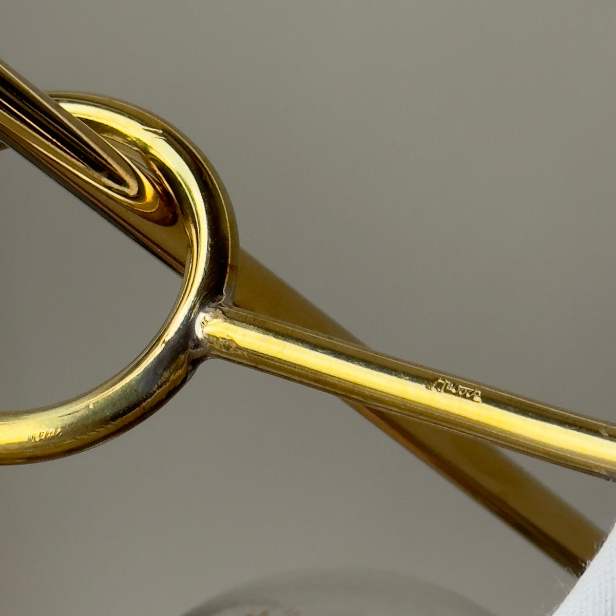 The X Lamp by Carl Auböck, featuring a modernist design with a conical shade, brass base, and bamboo stem. This versatile piece, which can be tilted or standing, is made in Vienna.