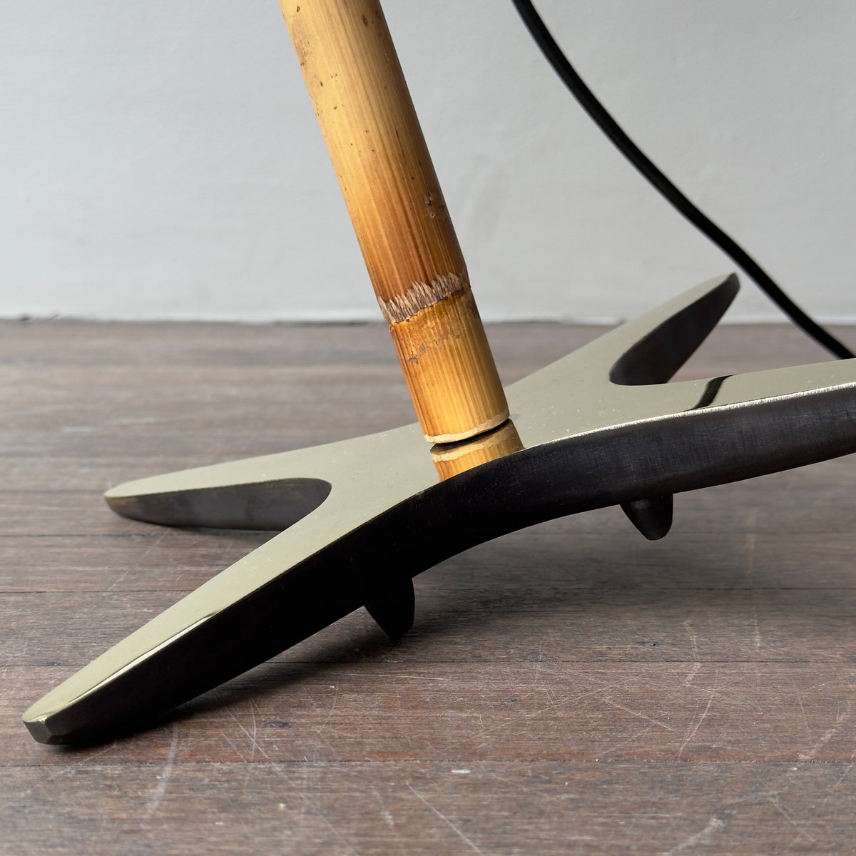 The X Lamp by Carl Auböck, featuring a modernist design with a conical shade, brass base, and bamboo stem. This versatile piece, which can be tilted or standing, is made in Vienna.