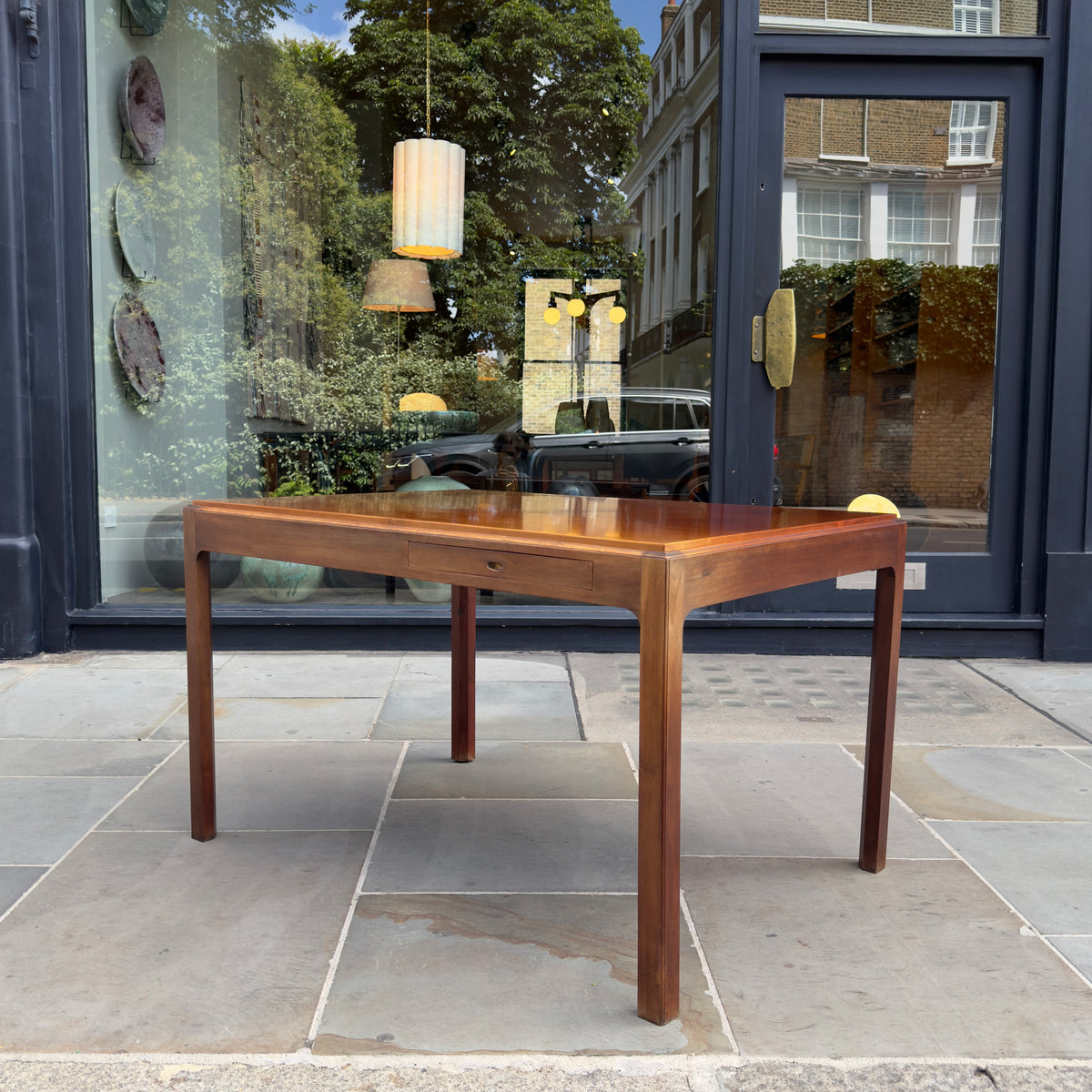 A 1950s Danish drafting table made of mahogany, featuring a reversible top, a drawer, and a central compartment. This piece combines functionality with classic mid-century design.