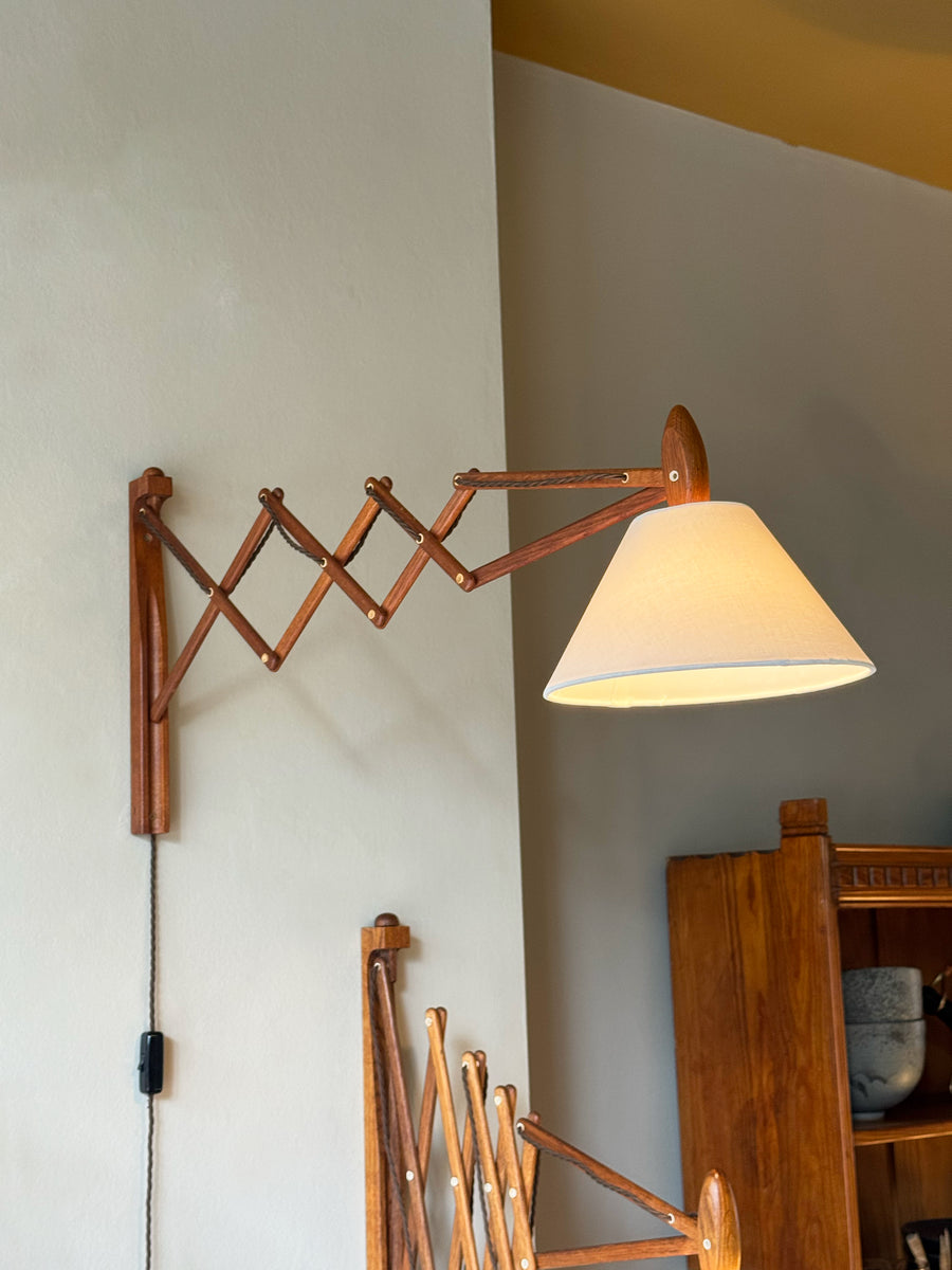 Wall-mounted lamp with a wooden arm and white shade on a neutral wall.