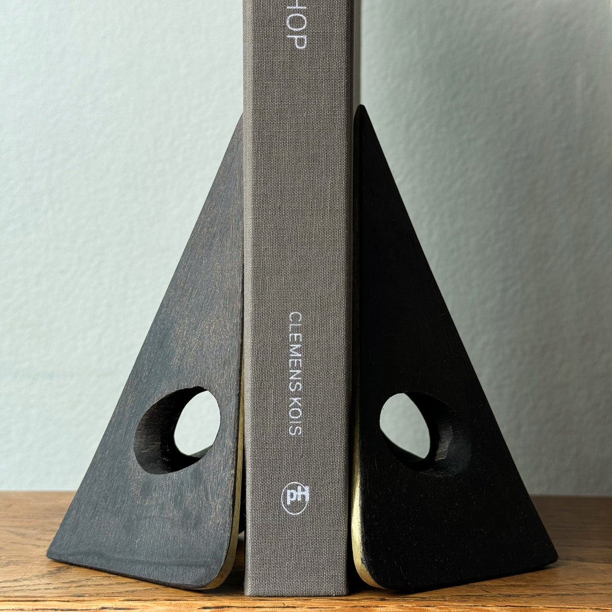 A solid cast brass bookend named 'Mask,' model 4100, designed by Carl Auböck. Based on a 1950s design, this piece is a sleek home accessory emblematic of modernist design.