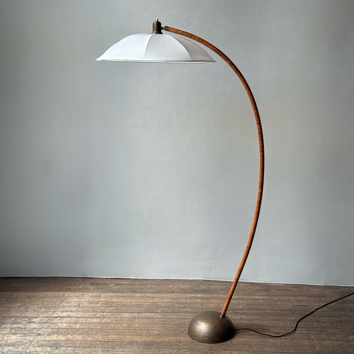 A leather bound arched floor lamp with weighted brass base and its original, custom sun-ray lampshade, recently restored with an ivory stretch silk.