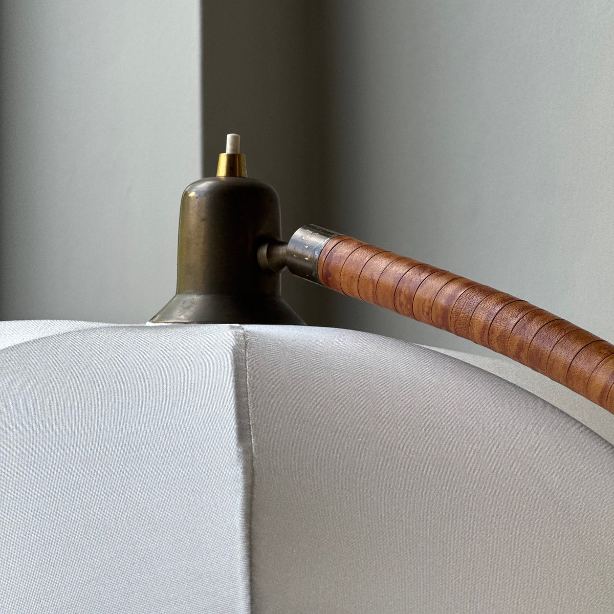 A leather bound arched floor lamp with weighted brass base and its original, custom sun-ray lampshade, recently restored with an ivory stretch silk.