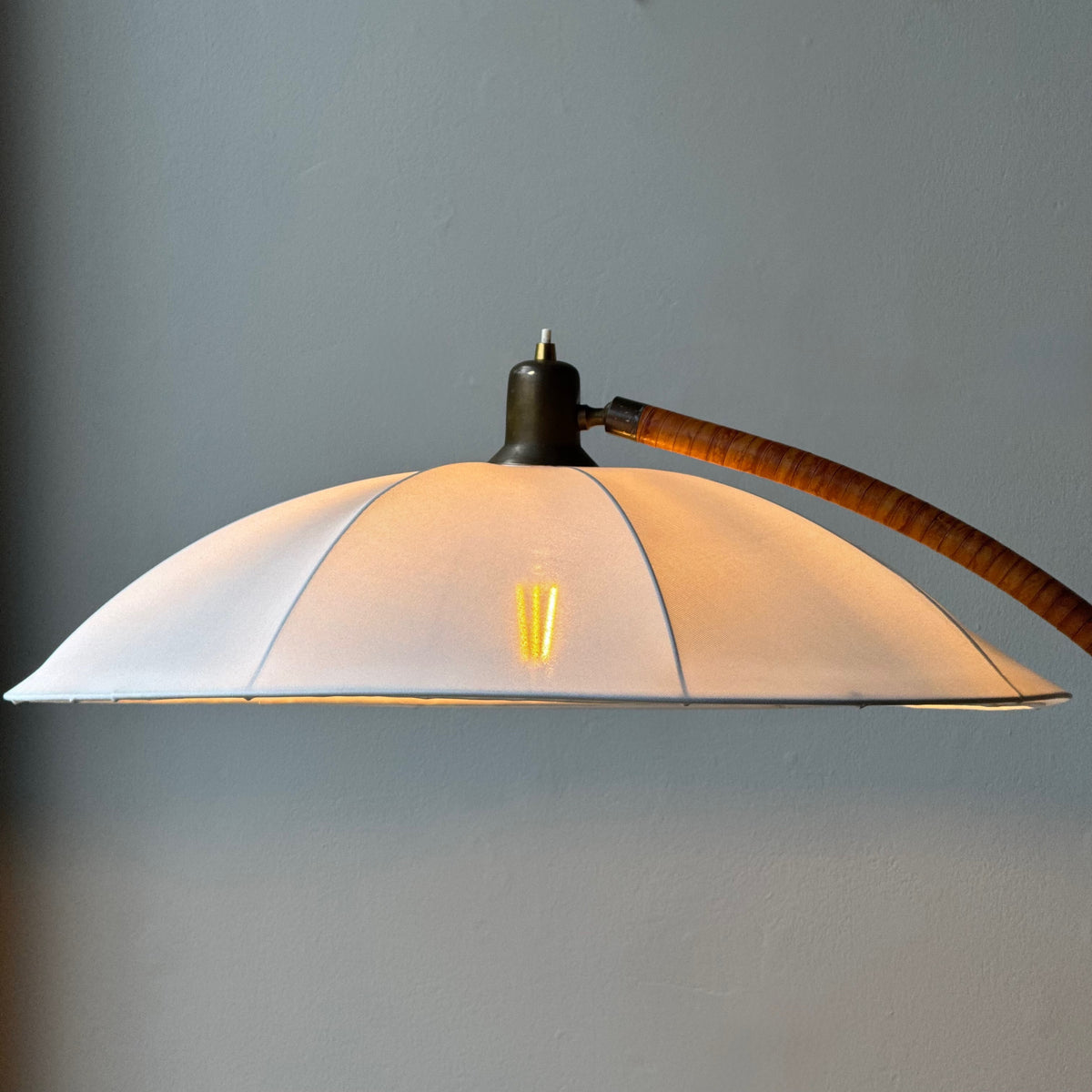 A leather bound arched floor lamp with weighted brass base and its original, custom sun-ray lampshade, recently restored with an ivory stretch silk.
