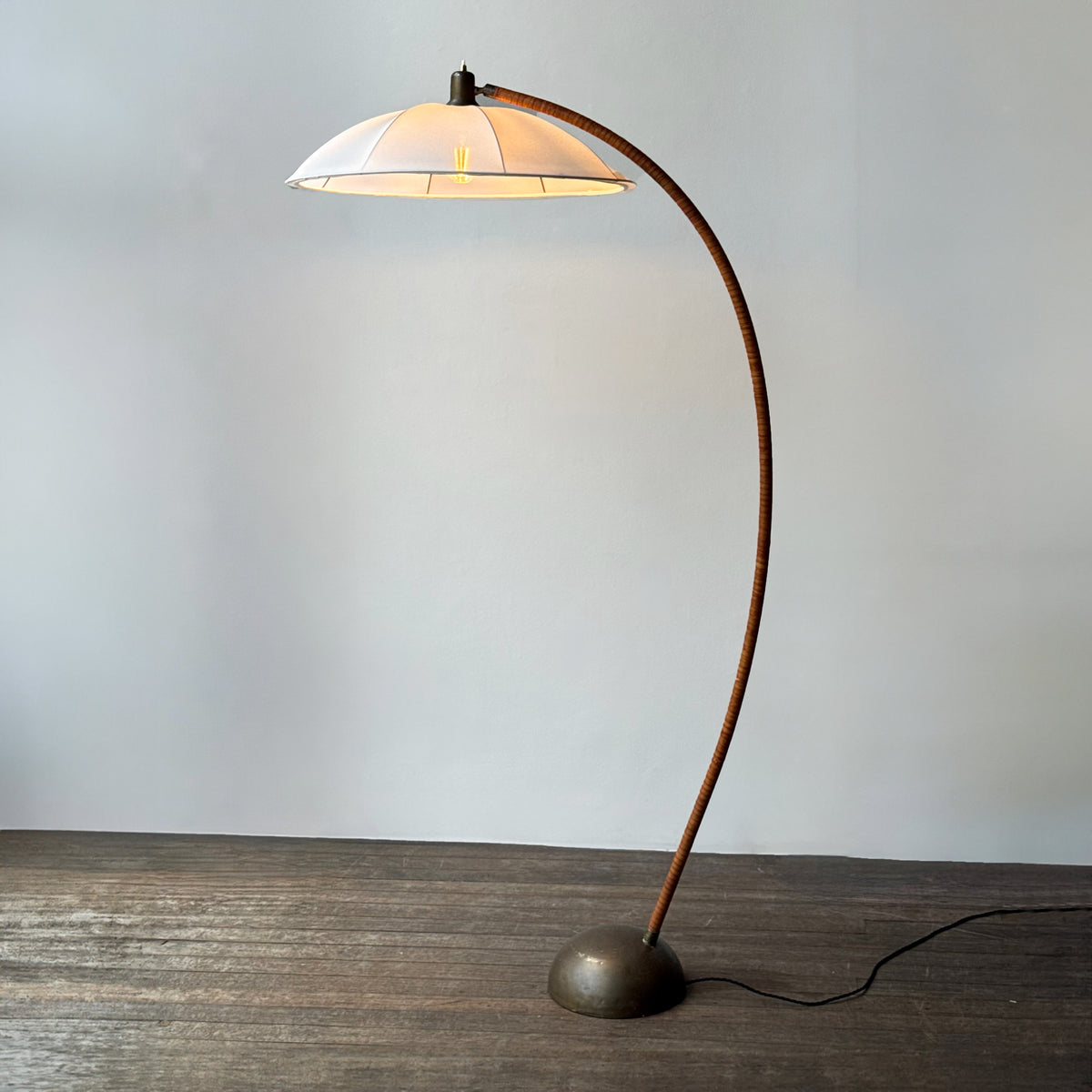 A leather bound arched floor lamp with weighted brass base and its original, custom sun-ray lampshade, recently restored with an ivory stretch silk.
