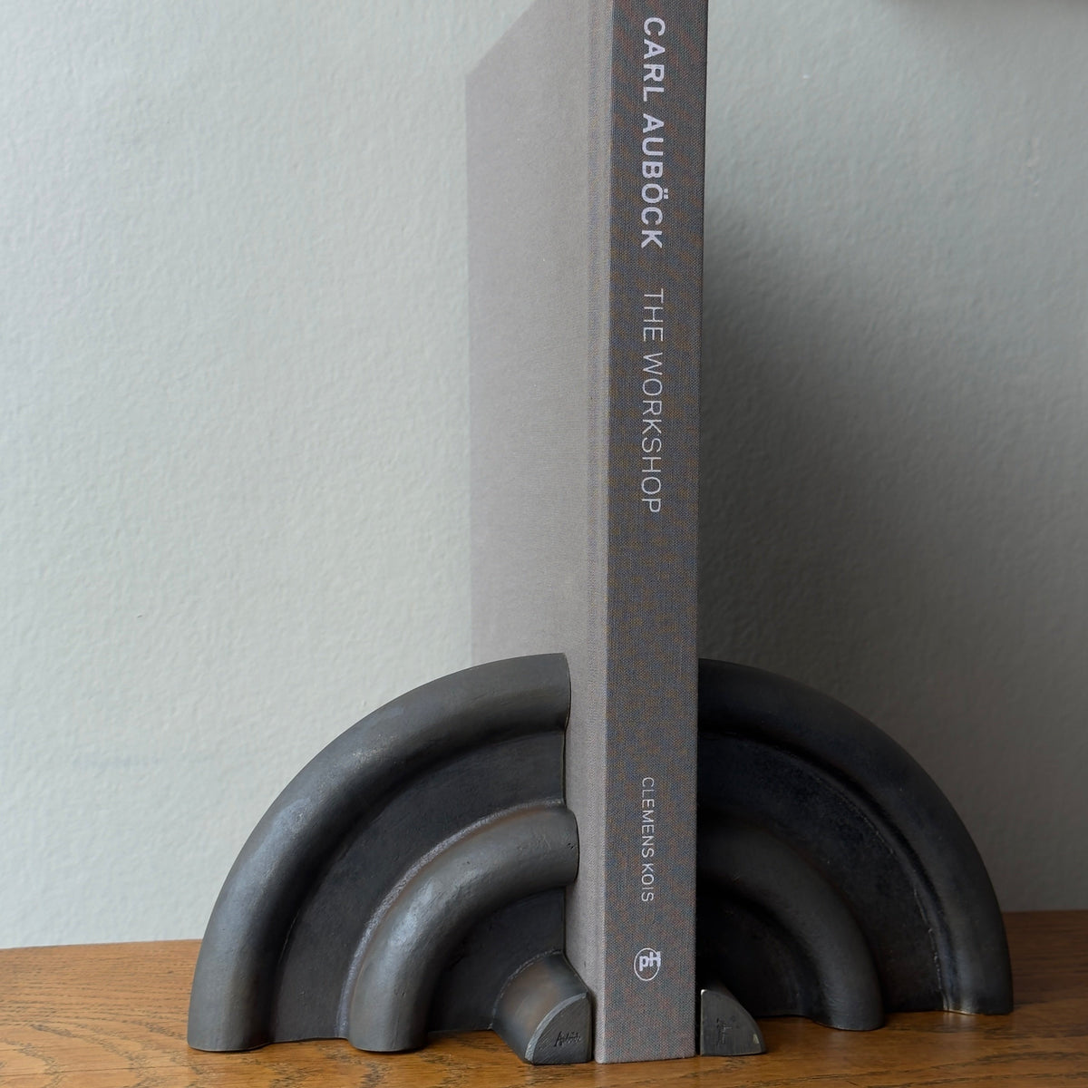 A cast brass bookend named 'Sun,' model 5533, designed by Carl Auböck and made in Vienna. This piece exemplifies modernist design with its sleek and artistic form.