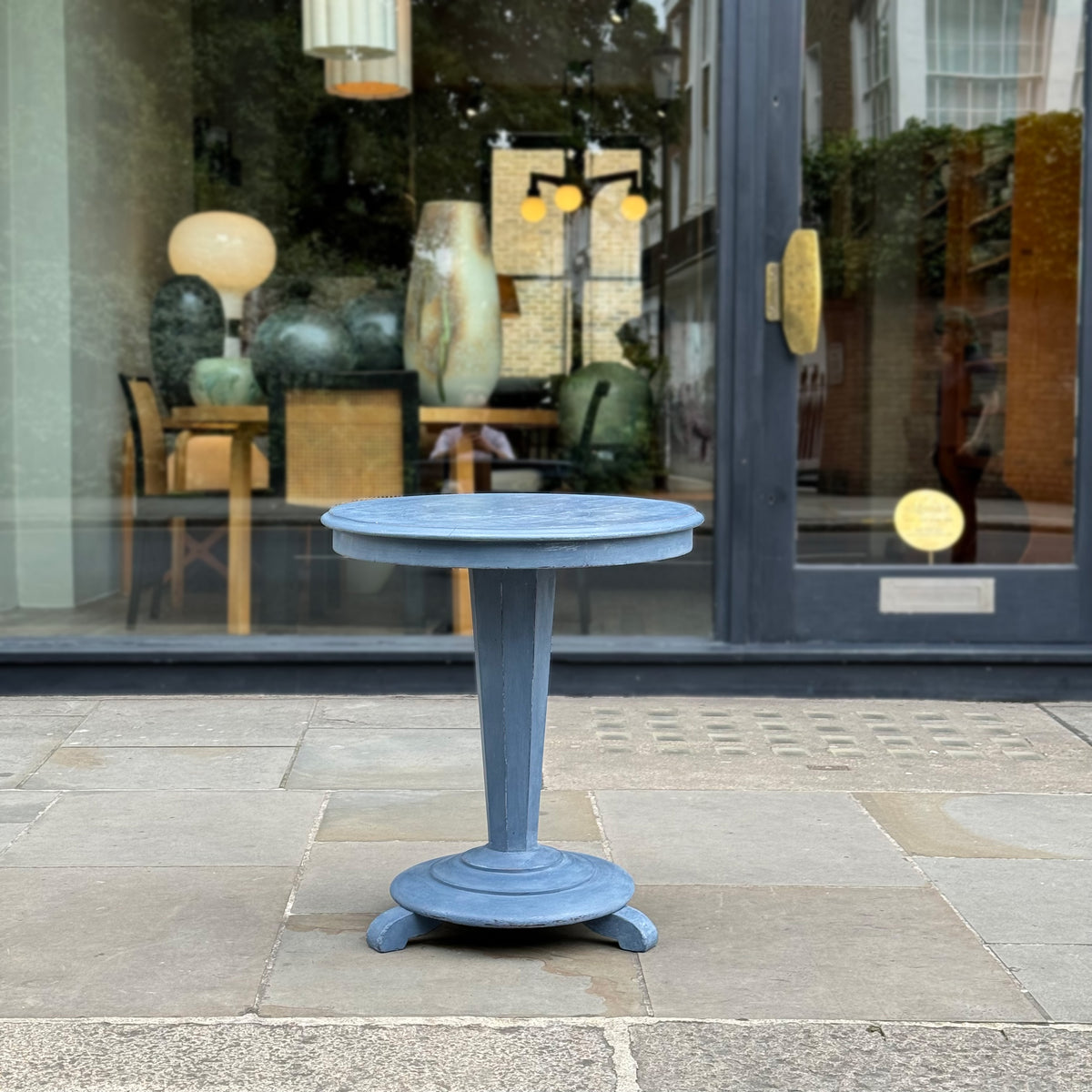 A swedish, blue painted mahogany table in front of Sigmar, a London design gallery and interior design studio. 