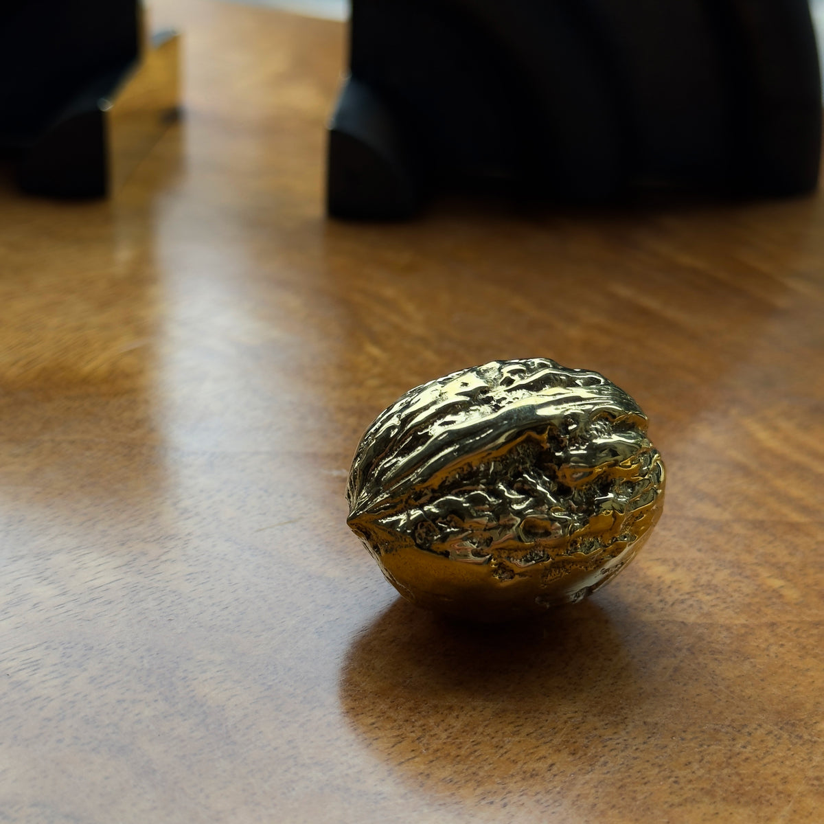 A walnut-shaped paperweight made of cast brass, created in Austria. This piece features modernist design with a blend of organic form and sleek craftsmanship.