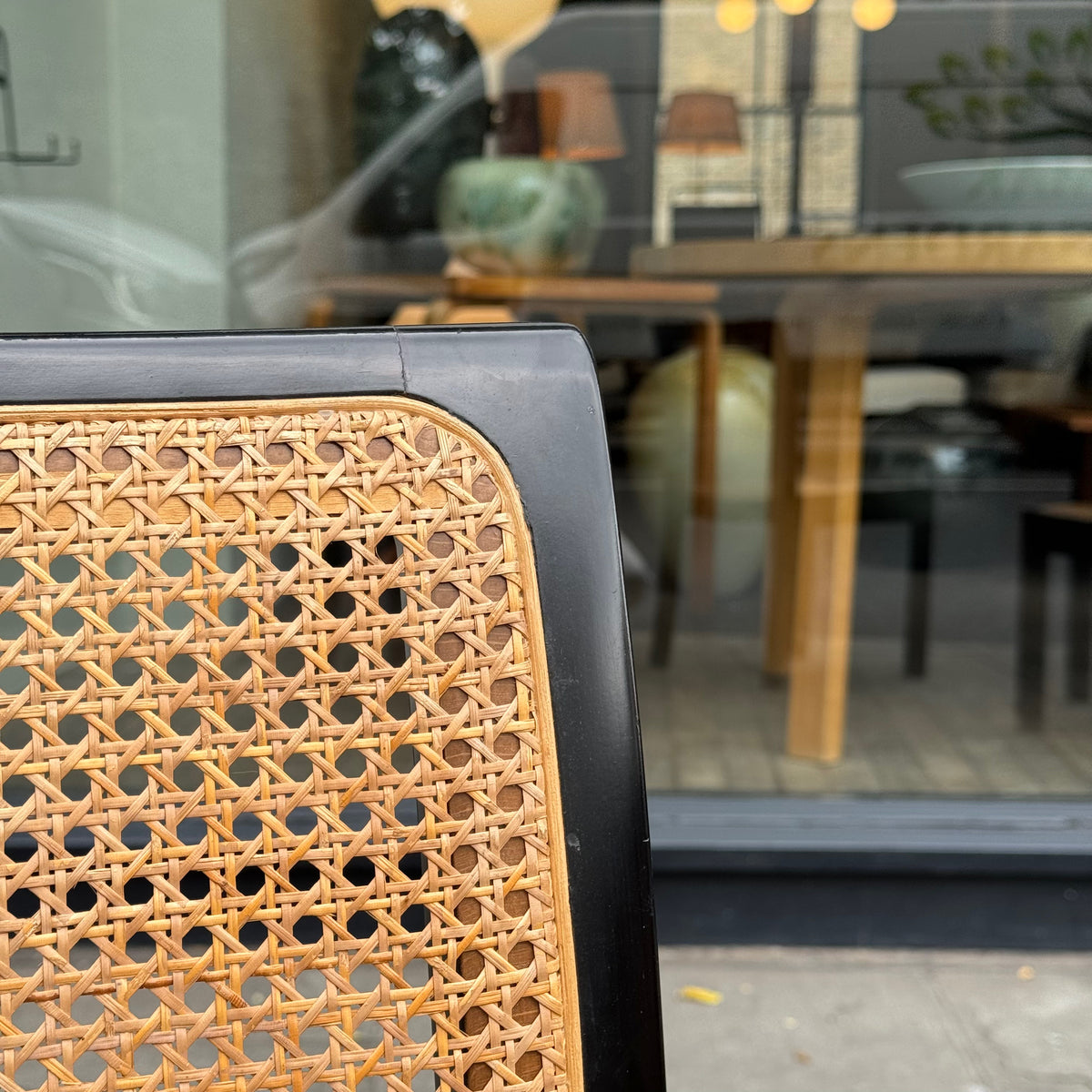Seat back detail of a Bankstuhl chair designed by Willy Guhl, featuring a sleek combination of black lacquered frames and cane seating. These chairs exemplify Guhl's innovative approach to design, blending elegant, modern aesthetics with functional comfort.