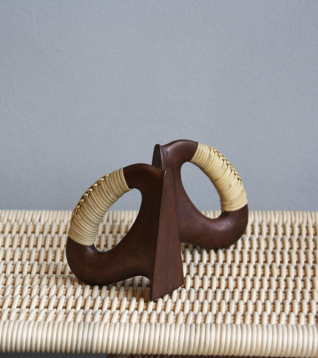 A pair of patinated flat iron bookends by Carl Auböck, crafted in the Werkstätte Auböck workshop, Vienna, Austria. Featuring blonde cane accents, these mid-century modernist pieces exemplify exceptional Austrian design and craftsmanship.