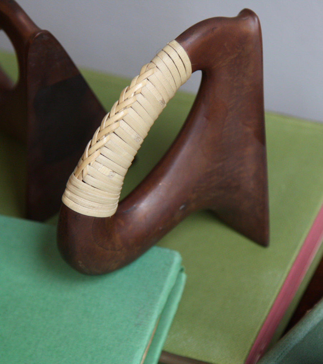 A pair of patinated flat iron bookends by Carl Auböck, crafted in the Werkstätte Auböck workshop, Vienna, Austria. Featuring blonde cane accents, these mid-century modernist pieces exemplify exceptional Austrian design and craftsmanship.