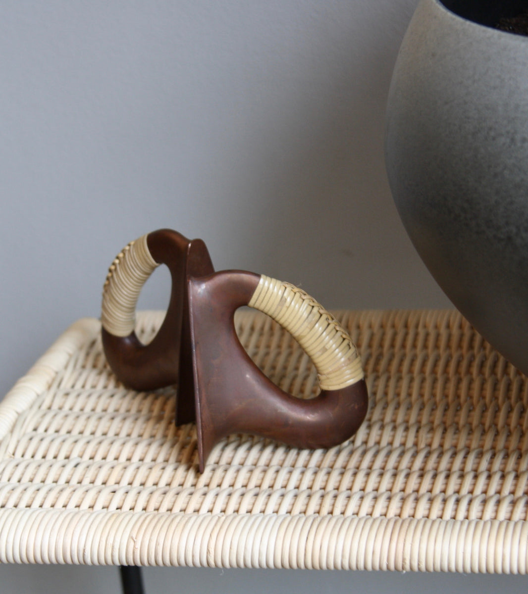 A pair of patinated flat iron bookends by Carl Auböck, crafted in the Werkstätte Auböck workshop, Vienna, Austria. Featuring blonde cane accents, these mid-century modernist pieces exemplify exceptional Austrian design and craftsmanship.